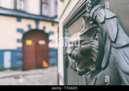 Bronze bas-relief of a cat's head with a fountain on the wall of a historic house in the old city of Riga Stock Photo