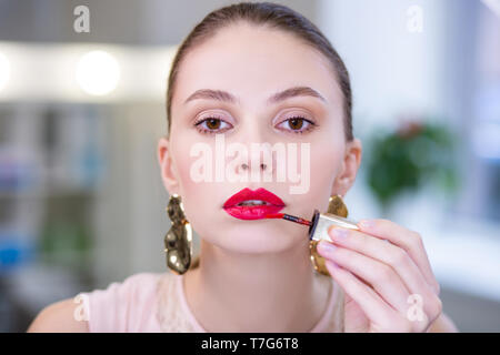 Portrait of a nice attractive woman putting on lipstick Stock Photo