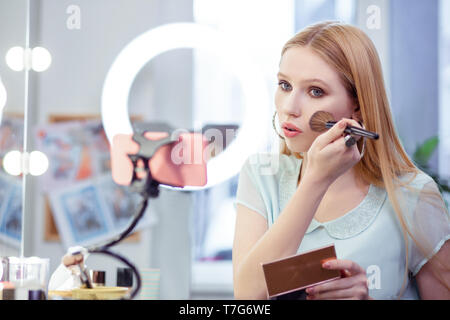 Nice pretty young woman applying facial foundation Stock Photo