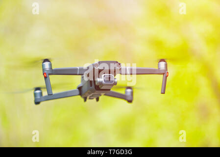 Flying drone with camera hovering inside a forrest, natural background Stock Photo