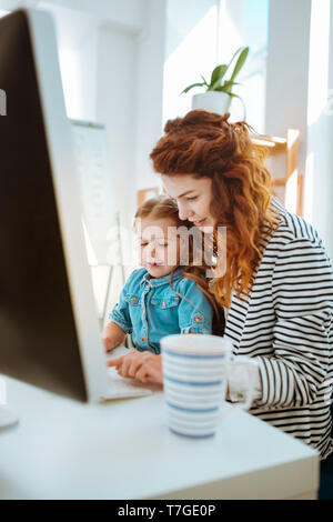 Woman working remotely spending time with her lovely daughter Stock Photo