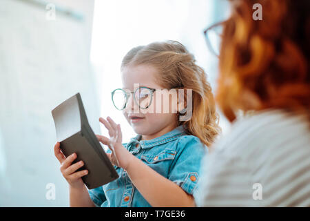 Daughter sitting near mom and using playing with calculator Stock Photo
