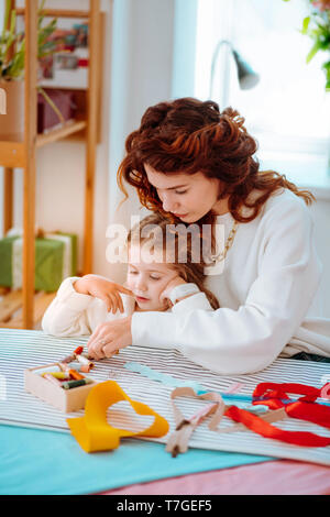 Mom playing with girl visiting her at the atelier during working day Stock Photo