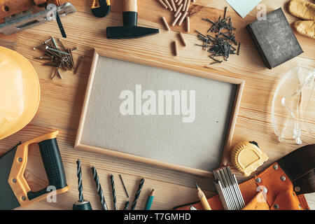 Empty picture frame as copy space mockup on carpentry woodwork desk among various tools of trade Stock Photo