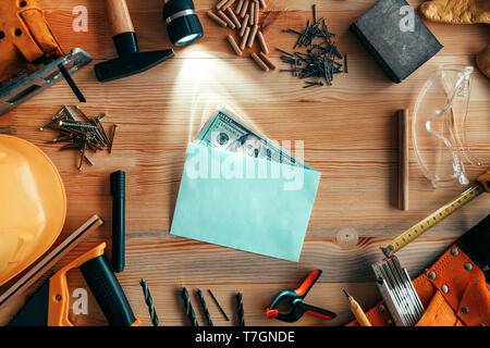 Money in envelope on carpentry woodwork workshop desk, top view Stock Photo