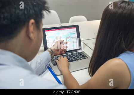 Asian office employees discuss about financial number on laptop Stock Photo