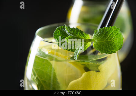 Mojito cocktail or lemonade with lime and mint in glass on black table. Close up. Summer refreshing drink. Space for text. Stock Photo