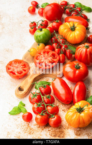 Selection of organic large heirloom and cherry tomatoes on white cream brown concrete background, selective focus Stock Photo