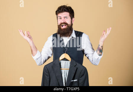 Getting excited about fashion. Emotional look of bearded fashion model. Fashion designer helping to choose suit jacket. Fashion stylist holding readymade formal coat. Stock Photo