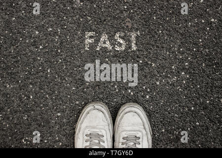 New life concept, Sport shoes and the word RUN written on asphalt ground, Motivational slogan. Stock Photo