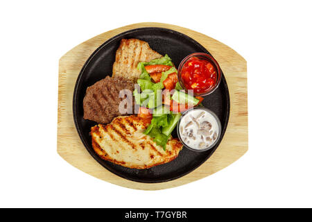 Three pieces of different types of meat with vegetable salad. Steak beef, pork, grilled meat, barbecue, on a plate with tomato, spicy, red sauce and t Stock Photo