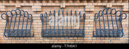 The fence of brickwork is decorated with a forged curly iron grating Stock Photo
