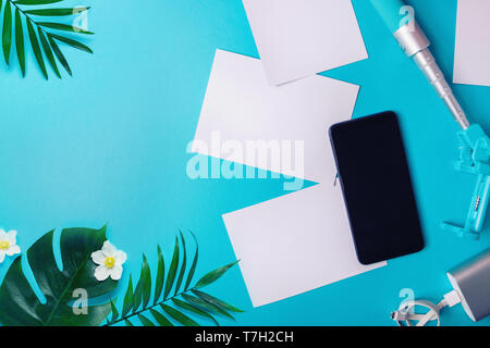 Smartphone with blank screen, flyers, photos on blue background. Mock up, flat lay Vacation concept Stock Photo