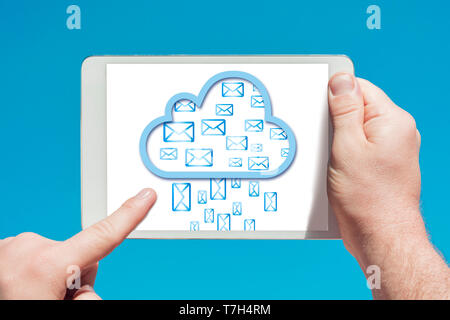 Man holding a tablet device and cloud computing communication icon to download stored data, touching the screen with a finger with blue sky Stock Photo