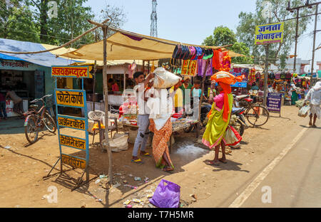Street scene in Shahpura, a Dindori district town in the central Indian state of Madhya Pradesh, local women carry  packages on their heads Stock Photo