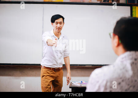 Asian man talking to student while having class in spacious auditorium Stock Photo