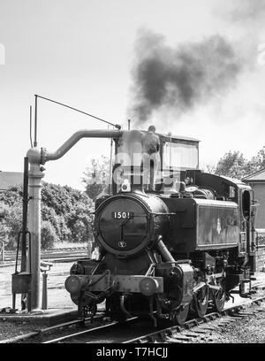 Monochrome vintage UK steam locomotive in sidings at Severn Valley Railway Kidderminster station taking on water, steam train crew by water stop crane Stock Photo