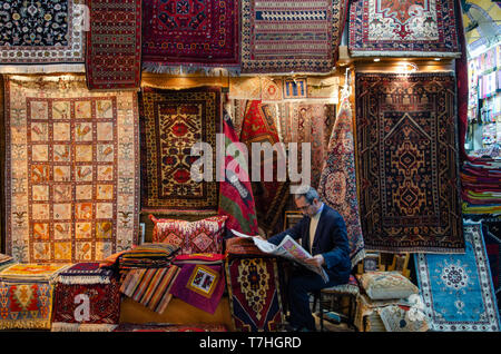 A Turkish carpet seller reading a newspaper inside the Grand Bazar, Istanbul, Turkey Stock Photo