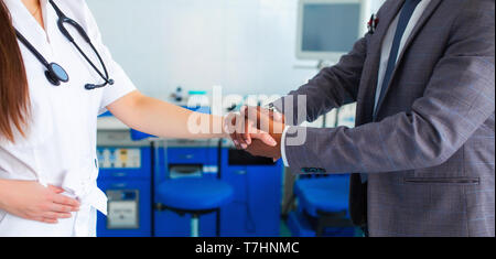 medicine, healthcare and technology concept - doctor with and male asian patient shaking hands at hospital. faceless background Stock Photo
