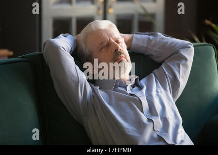 Sleeping grey haired man relaxing on comfortable sofa at home Stock Photo