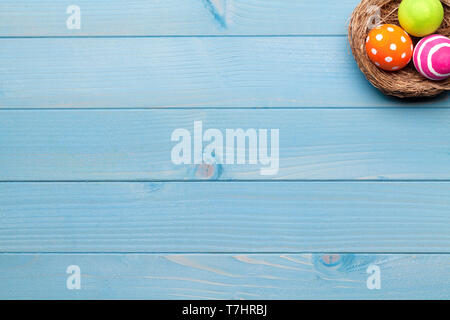 Colorful easter eggs in easter nest on blue wooden background Stock Photo