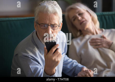 Mature man, husband calling emergency, woman, wife having heart attack Stock Photo