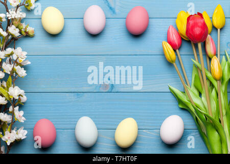 Colorful easter eggs and tulips on blue wooden background Stock Photo