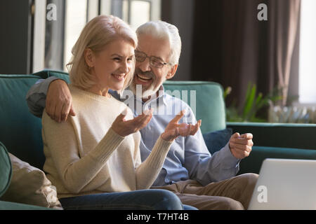Happy smiling mature family, wife and husband using laptop together Stock Photo