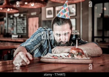 Displeased man examining his alternative to birthday cake. Stock Photo