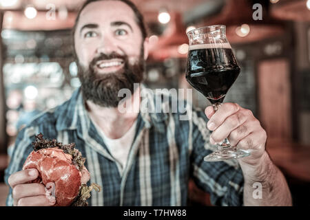 Amused bearded man holding his beer up. Stock Photo