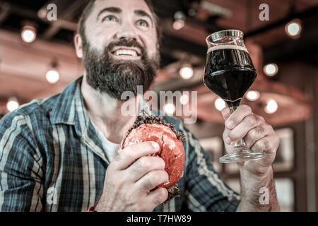 Pub guest watching a game and raising a glass. Stock Photo