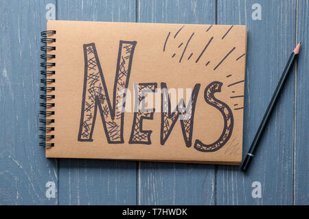 Notebook with written word NEWS on wooden background Stock Photo
