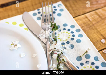 Table setting with white plate and spring flowers on wooden table, close-up view with selective focus. Springtime concept. Stock Photo