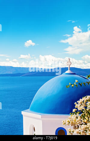 Santorini skyline with blue dome church and sky clouds background Stock Photo