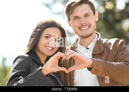 Lovely couple holding hands in shape of heart outdoors Stock Photo
