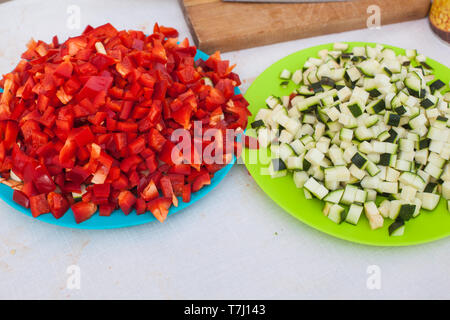 A blue plate full of diced red raw pepper and a green plate full of green raw diced zucchini ready to get in the pan Stock Photo