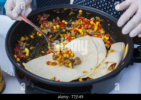 Close up of a child's hand filling up tortillas with roasted vegetables and beef meat Stock Photo
