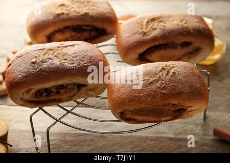 Cooling rack with sweet cinnamon buns on table Stock Photo