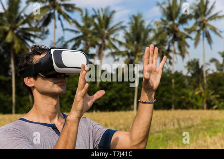 Young man wearing VR glasses in the tropical rice field Stock Photo