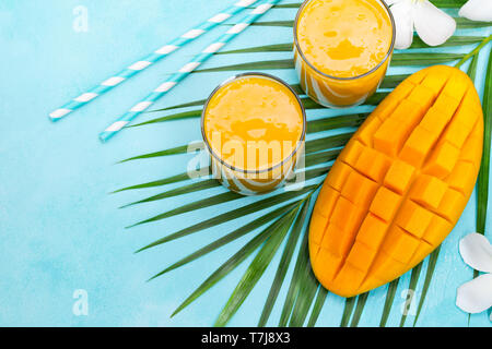 Fresh tropical fruit smoothie mango juice and fresh mango on blue background. Copy space. Top view. Stock Photo