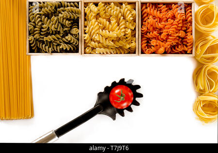 Multi-colored pasta in the form of spirals lie in wooden boxes that stand on a white table. isolated Stock Photo