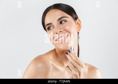 Beauty portrait of an attractive healthy woman standing isolated over white background, applying body oil Stock Photo