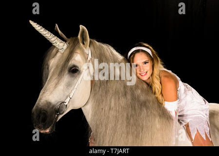 Young woman (fairy, virgin) on back of unicorn (Pure Spanish Horse with attached horn). Germany Stock Photo