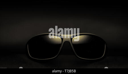 A Pair of dark framed sunglasses against a black background Stock Photo