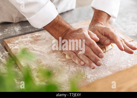 Closeup portrait of male hands making dough for bread on table at bakery or kitchen Stock Photo