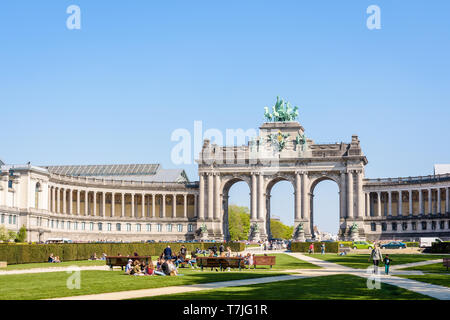 People enjoy a sunny day in the Cinquantenaire park in Brussels, Belgium, with the arcade du Cinquantenaire, the triumphal arch, in the background. Stock Photo