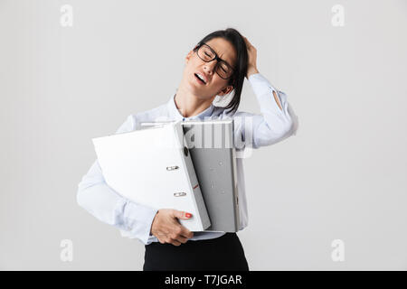 Photo of businesswoman wearing eyeglasses holding paper folders in the office isolated over white background Stock Photo