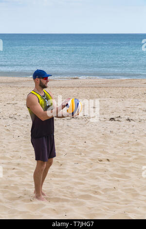 Beach volleyball player getting ready to serve at Boscombe Beach, Bournemouth, Dorset UK in May Stock Photo