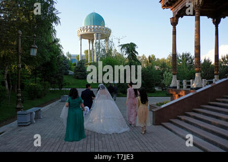 Locals taking part in a pre wedding photography session walk past the Museum of Victims of Political Repression which tells the history of Uzbekistan during the time of the Soviet Union located in Tashkent capital of Uzbekistan Stock Photo