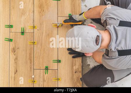 Professional Remodeling Worker Installing Wooden Like Ceramic Floor in the Kitchen Area. Home Renovation Project. Stock Photo